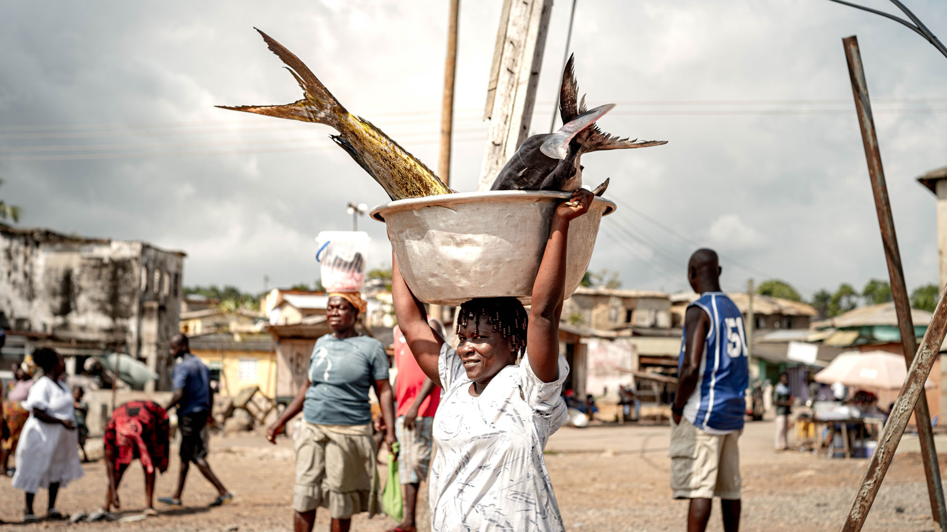 Woman carrying a bucket of fish on her head