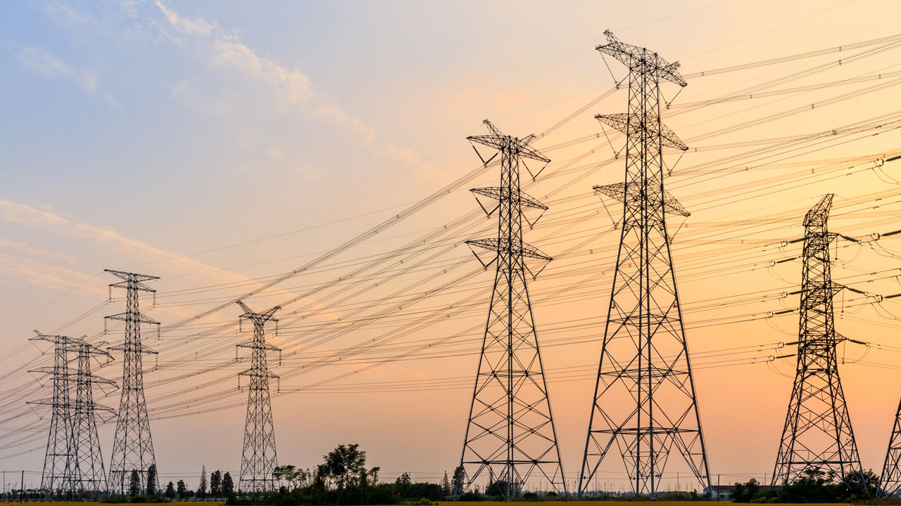High-voltage power transmission lines in front of a sunset