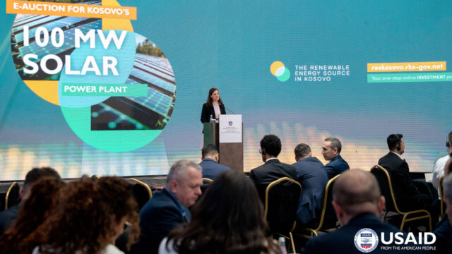 A person speaking at a podium at Kosovo’s first-ever renewable energy auction, which competitively solicited 100 megawatts of solar energy