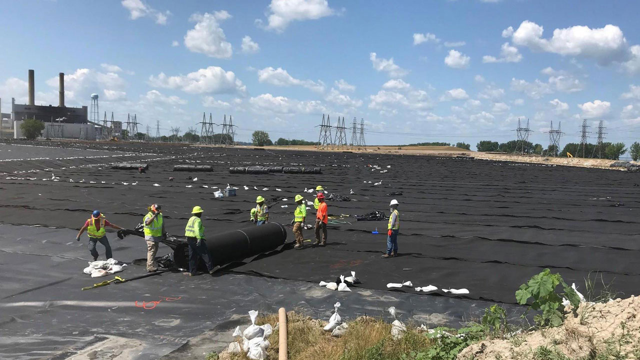 Liner crew installing geotextile over a previously installed geomembrane on a large coal ash closure at a power plant