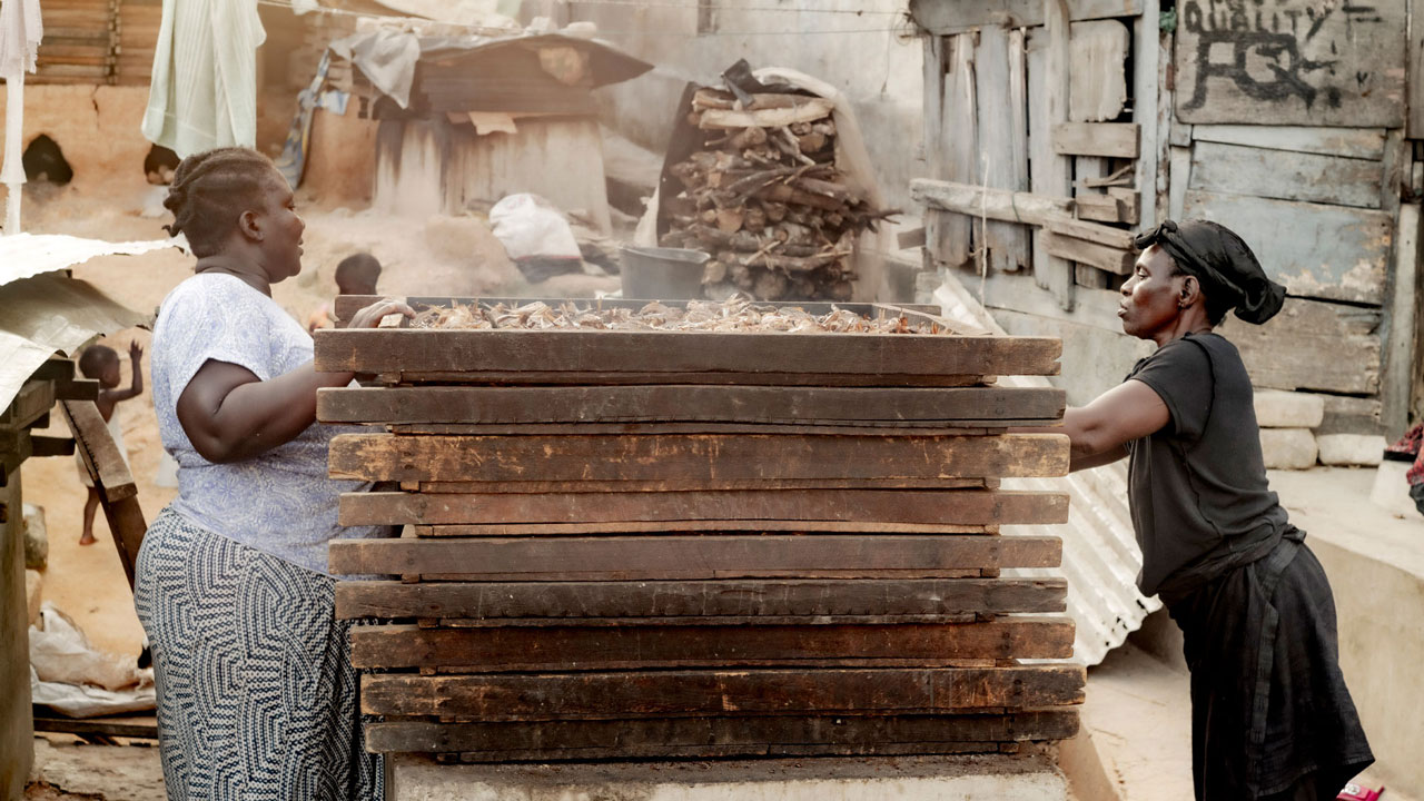 Two women working at a fish smoker 