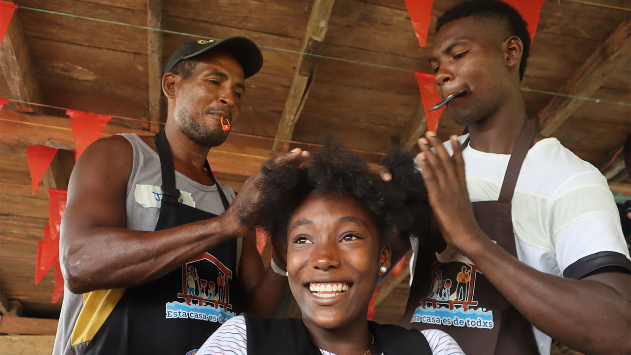 Young woman smiling while having her hair done by two men