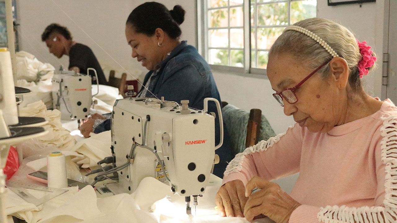 Woman building her sewing skills at a job training center, with other participants.in background