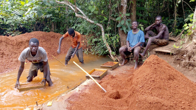 Four artisanal miners washing gravel in a river